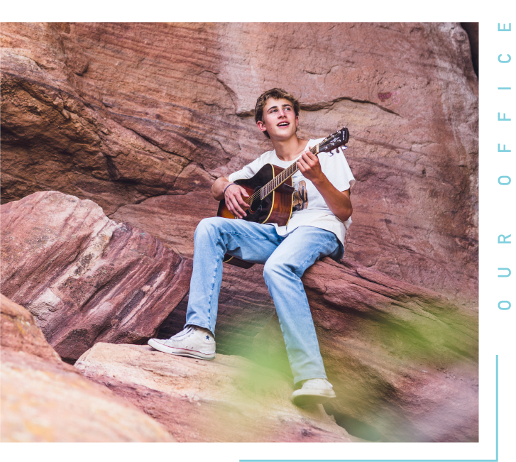 Boy playing the guitar on a rock formation