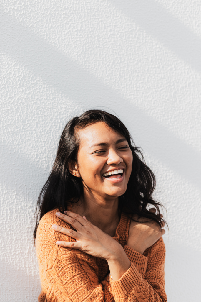 girl in aurora co laughing in an orange sweater